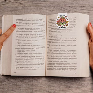 May include: A close-up of an open book with a bookmark featuring a pumpkin with a book and the text "Fall Bookish and Cozy Reads". The book is open to a page with text in Spanish.