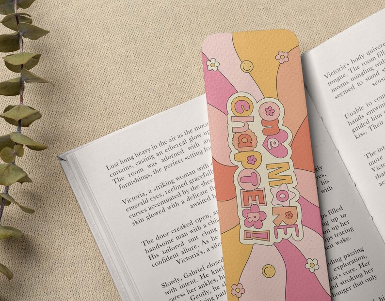 K&ouml;nnte beinhalten: Ein rosa und orangefarbenes Lesezeichen mit einem wellenf&ouml;rmigen Design und dem Text "One More Chapter!" in einer Retro-Schrift.