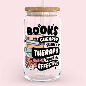 May include: A clear glass jar with a wooden lid and a straw. The jar has a colorful graphic that says "Books are cheaper than therapy and twice as effective".