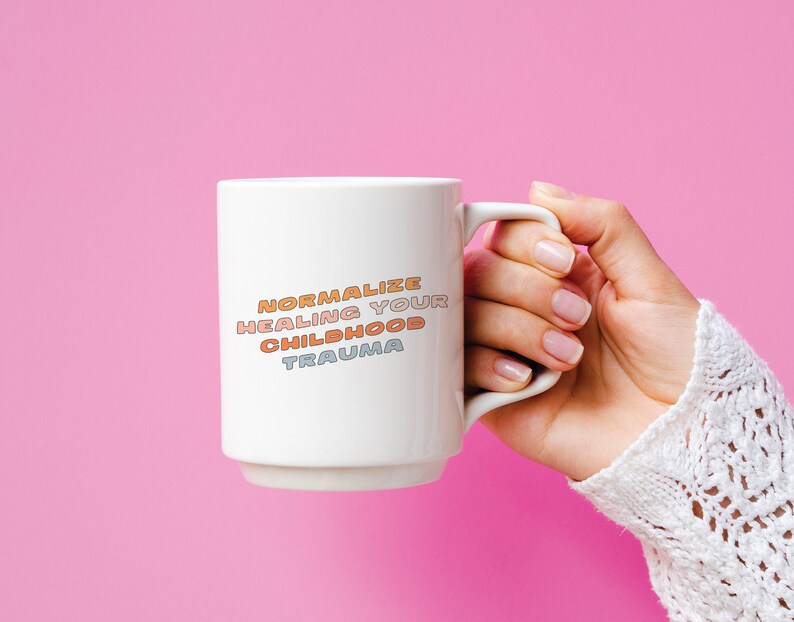 May include: White ceramic mug with the text "NORMALIZE HEALING YOUR CHILDHOOD TRAUMA" in colorful letters.