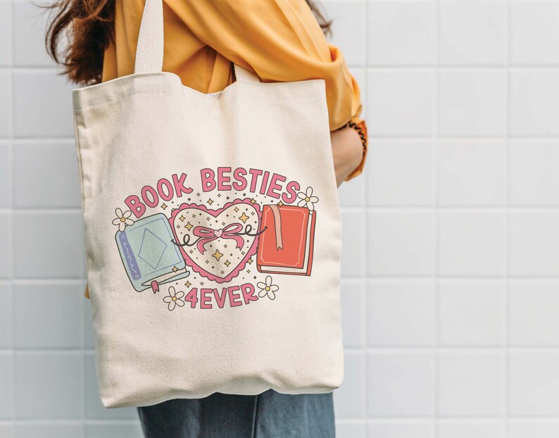May include: A white canvas tote bag with the text "Book Besties 4ever" and a pink heart with a bow and two books on either side. The books are blue and red.