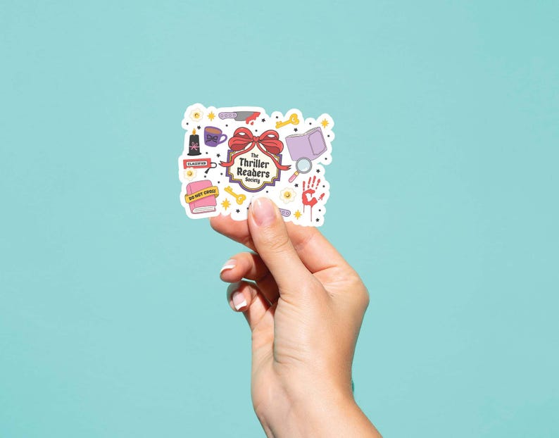 May include: A sticker with a collection of thriller-themed illustrations, including a knife, book, magnifying glass, and a handprint. The sticker has the text "The Thriller Readers Society" and is held against a teal background.