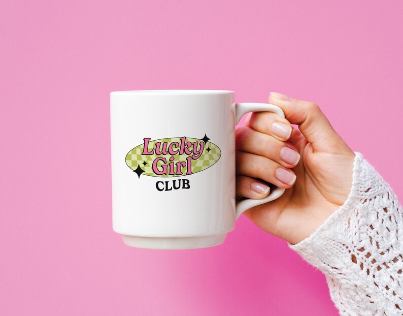 May include: White ceramic mug with a black and pink logo that says "Lucky Girl Club" on a yellow oval with a checkered pattern.