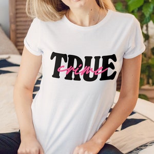 May include: White t-shirt with black text that says "TRUE crime" in a retro font. The word "crime" is in pink.