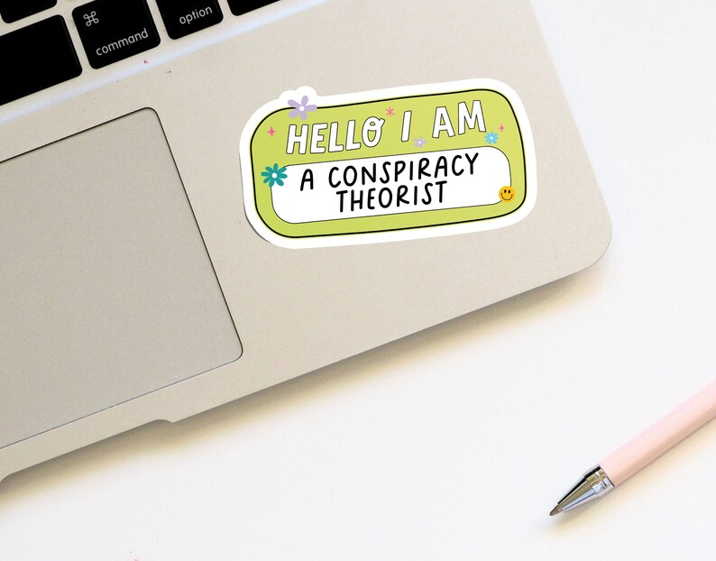 May include: A yellow sticker with rounded corners and a white border. The sticker says "Hello I am a conspiracy theorist" with a smiley face in the corner.