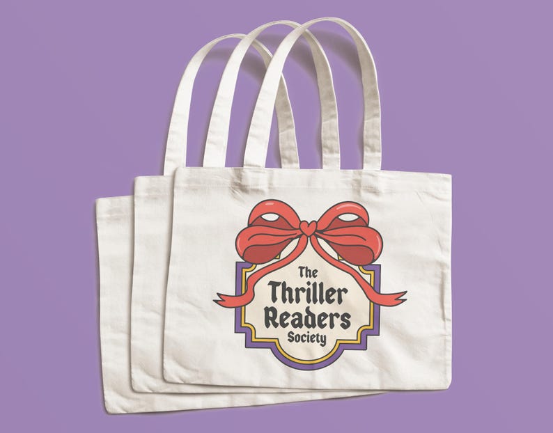 May include: Three white canvas tote bags with a red bow and ribbon design. The design includes the text "The Thriller Readers Society" in a vintage style. The bags have white handles and are set against a purple background.