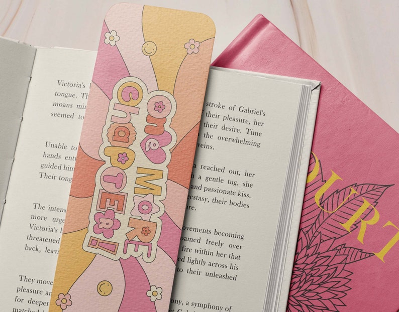 K&ouml;nnte beinhalten: Ein rosa und orangefarbenes Lesezeichen mit Retro-Design. Das Lesezeichen zeigt den Text "Chapter One More" in wei&szlig;er Schrift mit einem rosa Herzen.