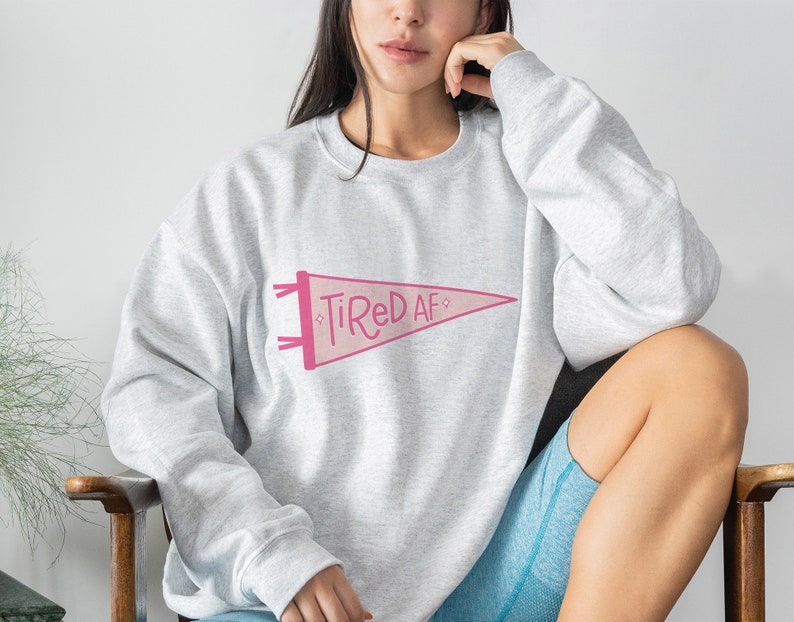May include: A gray sweatshirt with a pink pennant design that says "Tired AF".