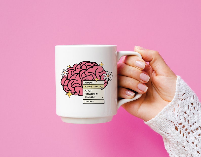 May include: White ceramic mug featuring a pink brain illustration and a yellow pop-up menu that reads "PROPERTIES: MANAGE ANXIETY, REFRESH, TROUBLESHOOT, BOUNDARIES, TURN OFF".