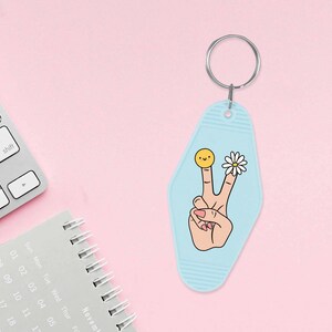 May include: A light blue motel key chain with a peace sign, a daisy, and a smiley face on it.