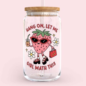 May include: A clear glass jar with a wooden lid and a straw. The jar has a cartoon strawberry with sunglasses and a shopping bag that says "Hang on, let me girl math this".