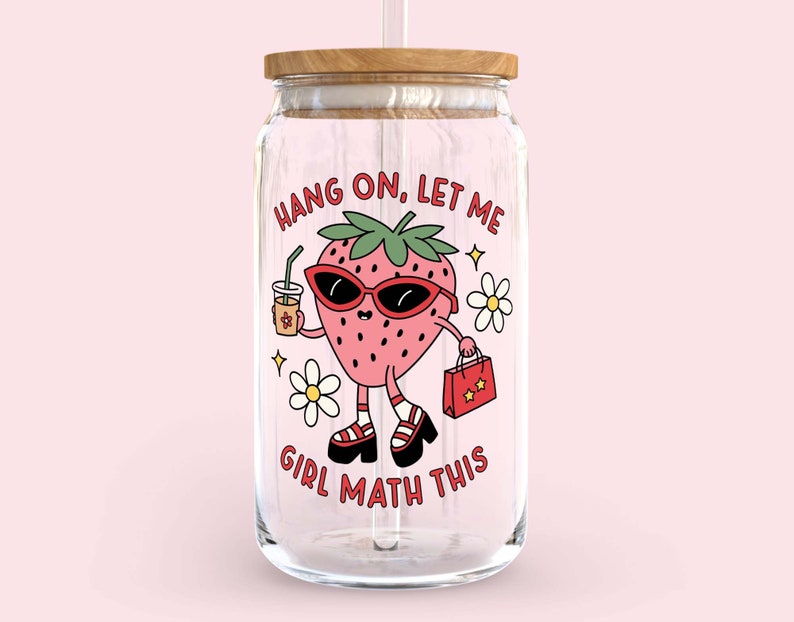 May include: A clear glass jar with a wooden lid and a straw. The jar has a cartoon strawberry with sunglasses and a shopping bag that says "Hang on, let me girl math this".