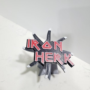 May include: A 3D printed black and red Iron Maiden logo with a star-shaped base.