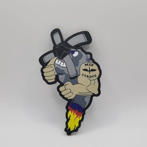 May include: A cartoon illustration of a gray engine with a black propeller and a muscular arm with a tattoo that says "Max Torque". The engine is on fire and has a determined expression.