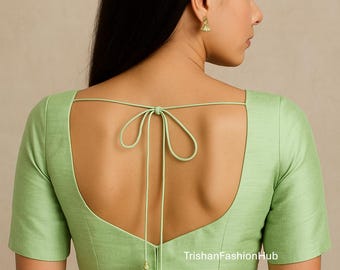 Puede incluir: Una blusa verde claro con mangas cortas y cuello redondo. La espalda presenta un cierre de lazo con borlas. El texto "TrishanFashionHub" es visible en la parte inferior derecha de la blusa.