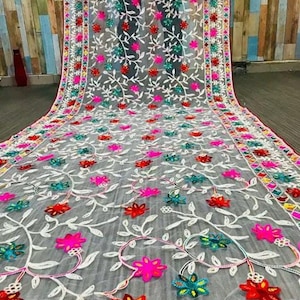 May include: White sheer fabric with colourful floral embroidery. The embroidery features pink, red, blue, green, and white flowers and leaves.