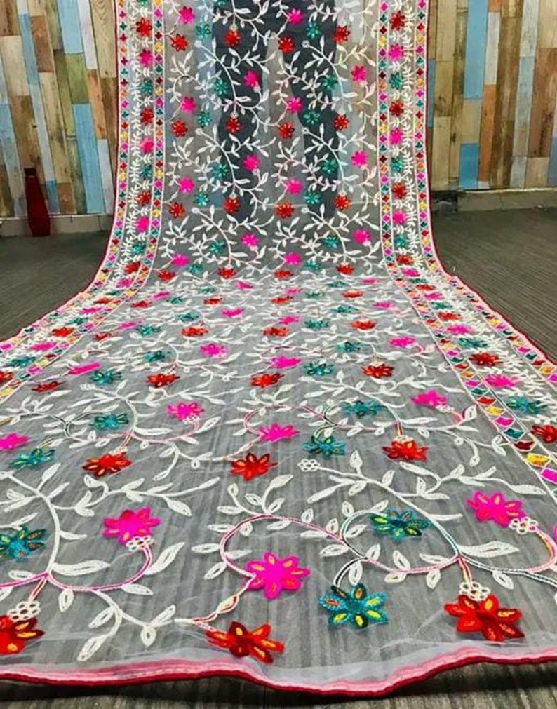 May include: White sheer fabric with colourful floral embroidery. The embroidery features pink, red, blue, green, and white flowers and leaves.