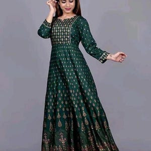 May include: A long green dress with a gold print. The dress has a round neckline and three-quarter sleeves.