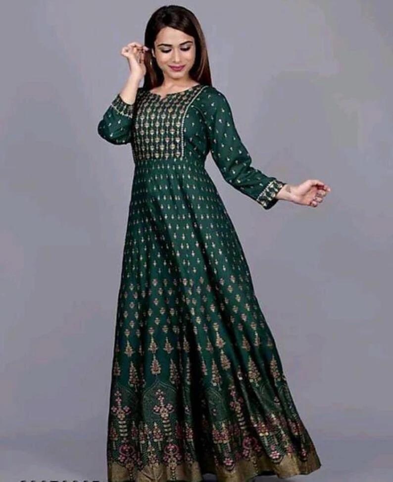 May include: A long green dress with a gold print. The dress has a round neckline and three-quarter sleeves.