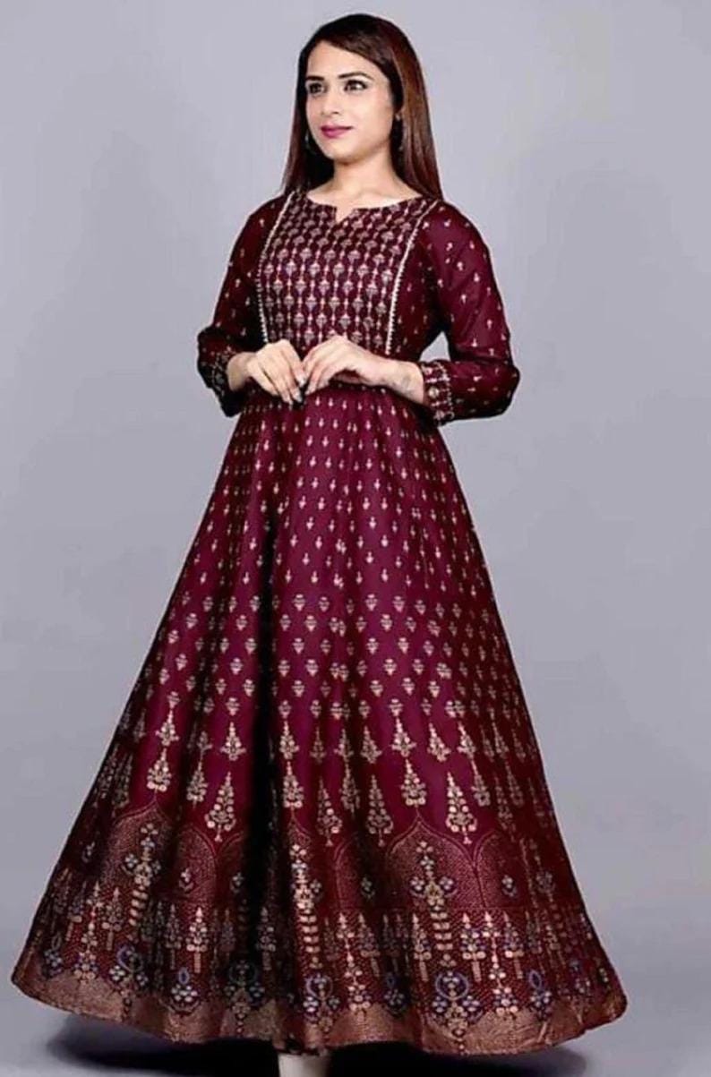 May include: A maroon maxi dress with a gold print. The dress has a round neckline and three-quarter sleeves. The dress is made of a soft, comfortable fabric.
