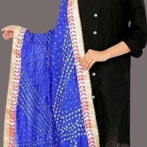 May include: A vibrant blue dupatta with a white dotted pattern and gold trim. The scarf is draped over a black top and white leggings. The dupatta's border has a pink and gold design.