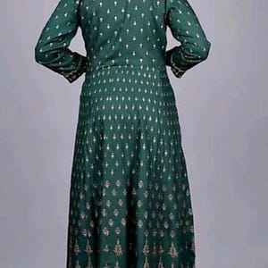 May include: A long green dress with a gold and white pattern. The dress has a V-neck and long sleeves.