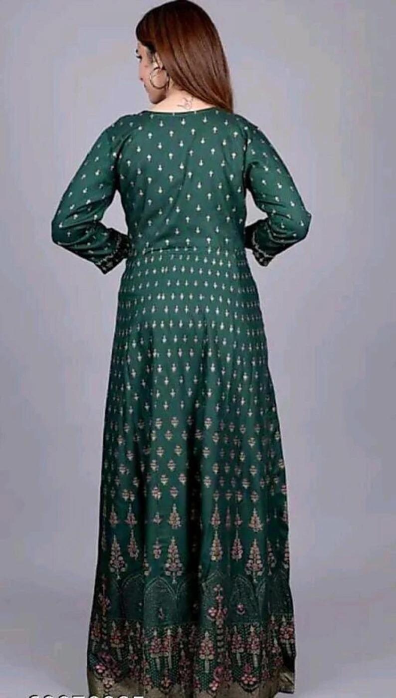 May include: A long green dress with a gold and white pattern. The dress has a V-neck and long sleeves.