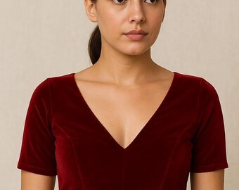 May include: A burgundy velvet top with a deep V-neck and short sleeves. The fitted top features the text "TrishanFashionHub" at the bottom. This is a piece of clothing.
