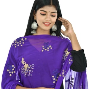 May include: A sheer purple scarf with embroidered floral and peacock feather designs in gold and navy blue. The scarf is draped over a black garment. The scarf is a vibrant accessory.