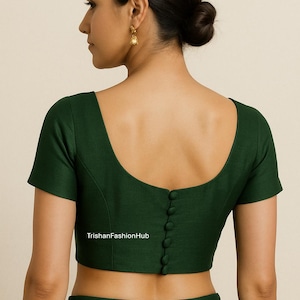 Puede incluir: Una blusa verde oscuro con mangas cortas y cuello redondo. La parte trasera de la blusa tiene una fila de botones. El texto "TrishanFashionHub" es visible en la parte inferior de la blusa.