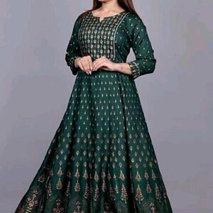 May include: A long, green maxi dress with a gold floral print. The dress has a V-neckline and three-quarter sleeves.