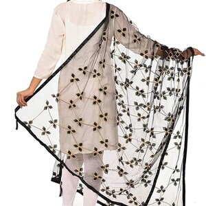 May include: Black net dupatta with gold embroidery and black trim. The dupatta is sheer and has a floral design.