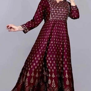 May include: A maroon maxi dress with a gold print. The dress has a V-neckline and three-quarter sleeves.