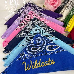 Puede incluir: Una colecci&oacute;n de pa&ntilde;uelos de algod&oacute;n doblados en varios colores, incluyendo azul real, azul claro, marino, rosa, morado y amarillo, todos con un patr&oacute;n de cachemira tradicional. El pa&ntilde;uelo azul real tiene la palabra Wildcats bordada en oro.