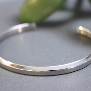 May include: A silver bangle bracelet with a smooth, polished finish.