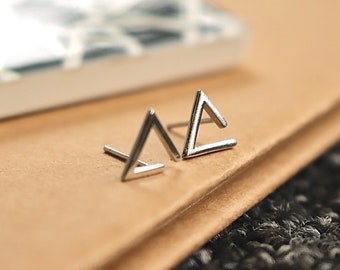 May include: A pair of silver triangle stud earrings. The earrings are simple and modern, and would make a great gift for a friend or loved one.