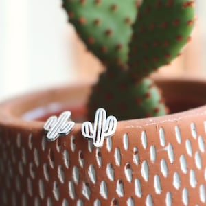 Op de afbeelding: Een paar zilveren cactus oorbellen. De oorbellen zijn klein en delicaat en perfect om een ​​toetsje whimsy aan elke outfit toe te voegen.