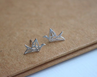 May include: A pair of silver origami crane earrings. The earrings are made of a delicate, geometric design and are perfect for adding a touch of elegance to any outfit.
