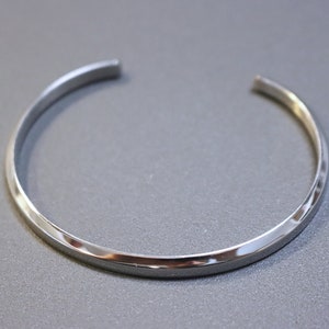 May include: A silver bangle bracelet with a smooth, polished finish.