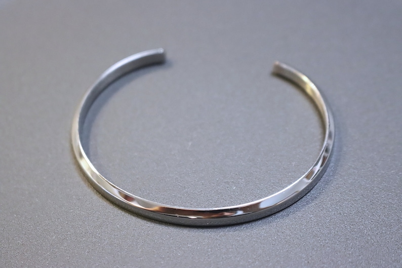 May include: A silver bangle bracelet with a smooth, polished finish.