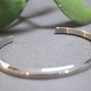 May include: A silver bangle bracelet with a smooth, polished finish.