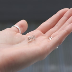 May include: A pair of silver triangle stud earrings with a spiral design.