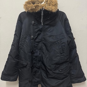 Könnte beinhalten: Schwarzer Winterparka mit Kapuze mit Kunstfellfutter. Die Jacke hat eine Knopfleiste vorne, mehrere Taschen und einen Reißverschluss. Der Parka ist für kaltes Wetter konzipiert und hat einen klassischen, zweckmäßigen Stil.