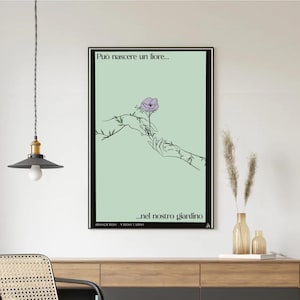 Può includere: Stampa artistica incorniciata con un'illustrazione minimalista di due mani che raggiungono un fiore viola. Lo sfondo è verde chiaro, con testo italiano in alto e in basso.