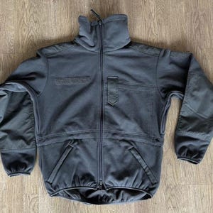 May include: A dark gray fleece jacket with a zipper closure and two pockets. The jacket has a high collar and a relaxed fit.