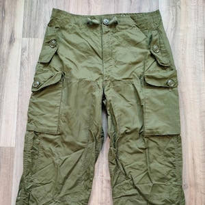 Pode incluir: Uma calça cargo verde oliva com vários bolsos e cintura com cordão.