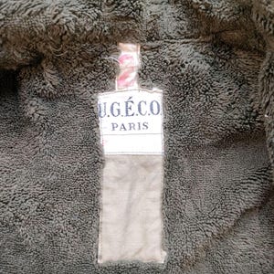 Może przedstawiać: Zbliżenie na brązową kurtkę z polaru z beżową metką z napisem "U.G.&Eacute;.CO. PARIS".