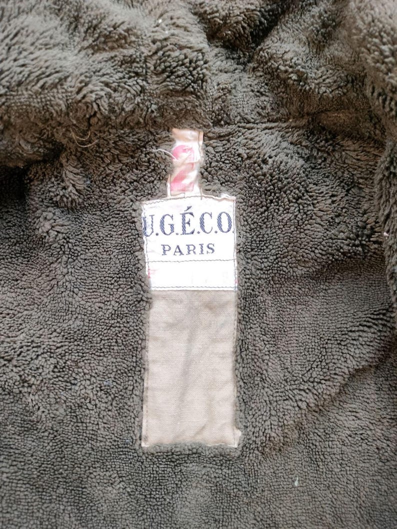 Może przedstawiać: Zbliżenie na brązową kurtkę z polaru z beżową metką z napisem "U.G.&Eacute;.CO. PARIS".