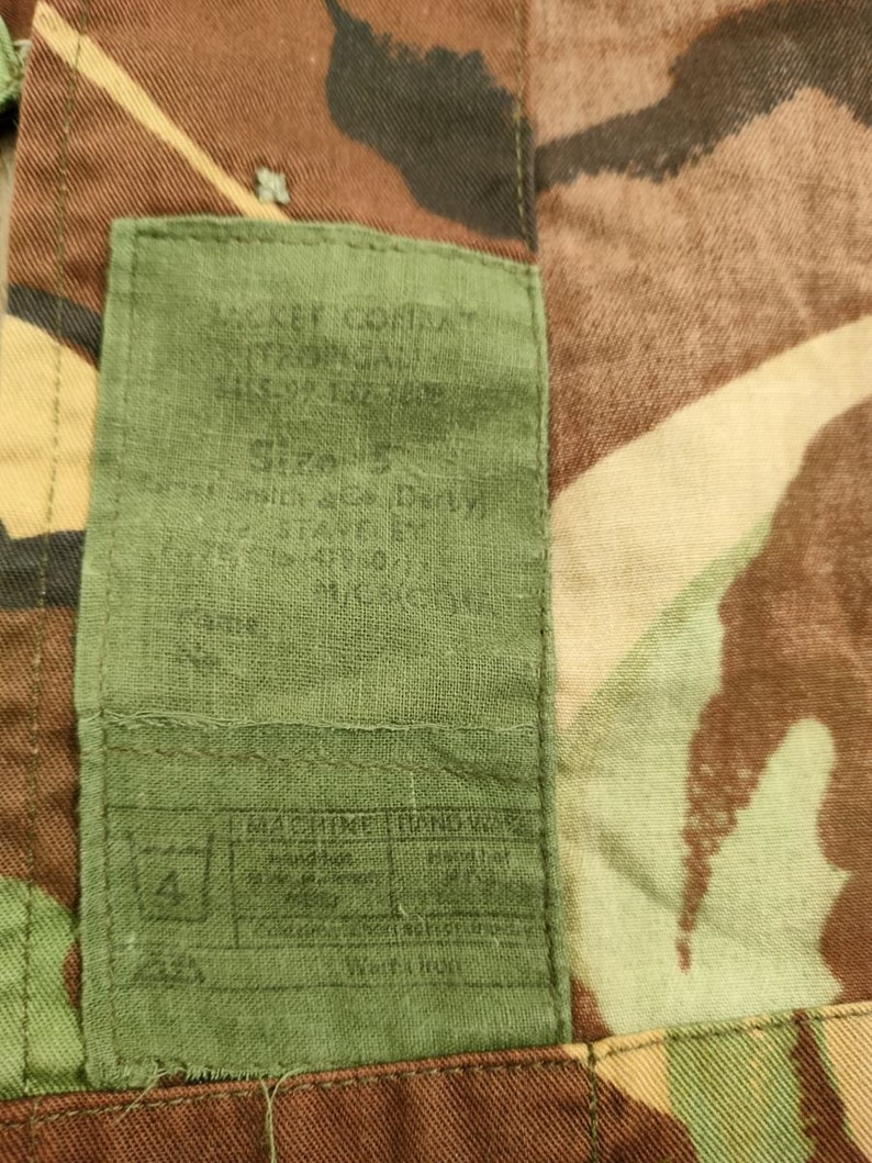 May include: A green fabric label with the text "M.S.E.F. COMBAT", "U.S. ARMY ISSUE", "SIZE 2", "D.I.Y.", "MACHINE WASHABLE", "HAND WASH", "Tumble Dry", "Do Not Bleach", "Iron Low", "Do Not Dry Clean", and "SIZE 2" printed on it.