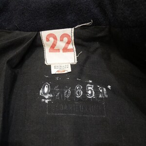 May include: A black fabric label with white text that reads "22" and "MITIN ANTINITIF" and a black stamp with the number "046651".